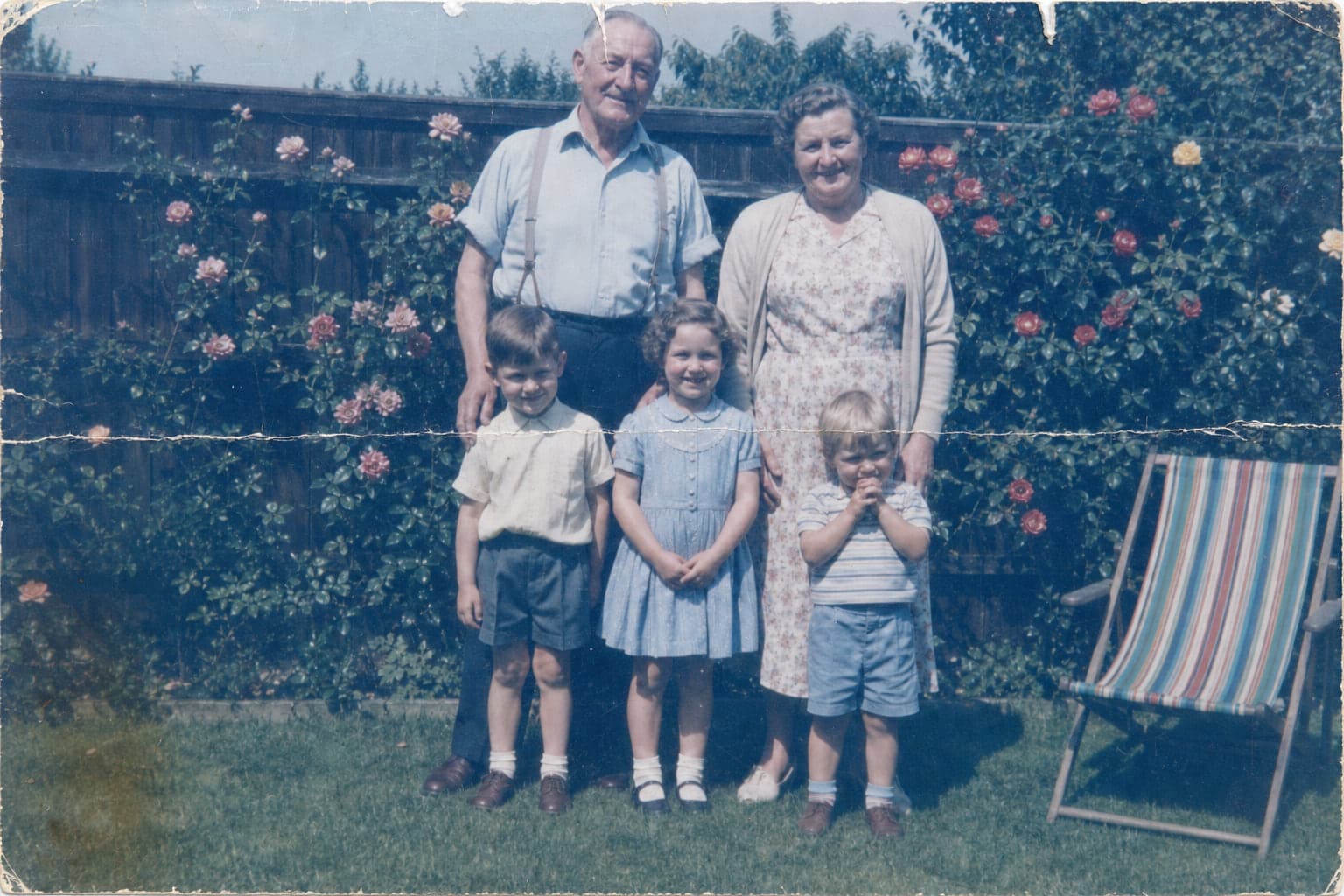 A faded blue colour photo of grandparents and children in a garden